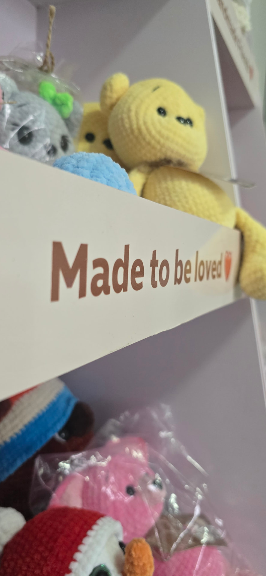 Made to be loved shelf label with crochet toys on a Dana Toys stand